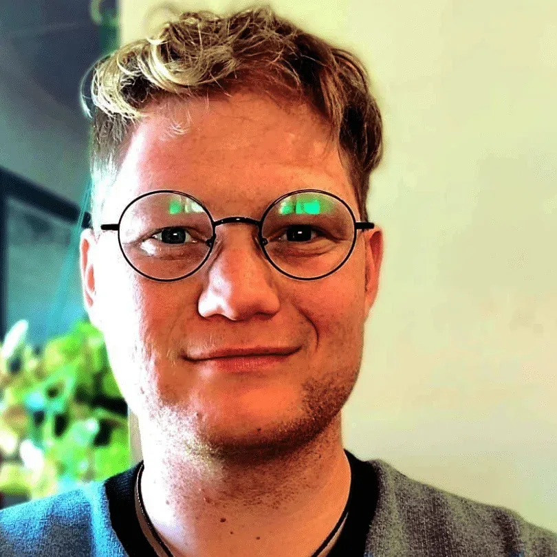 Portrait of JJ, wearing round glasses.
