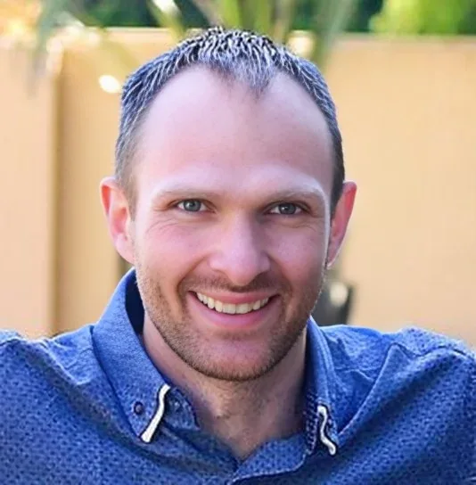 Portrait of Ryan, outdoors, in a blue shirt.