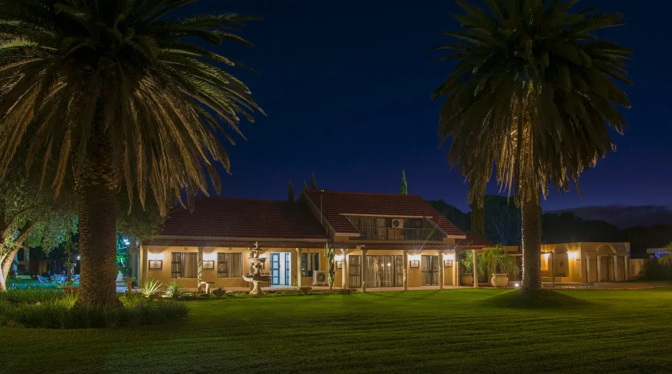 Tuscana Estate at night, the lit house and lawn where local networking gatherings are held.